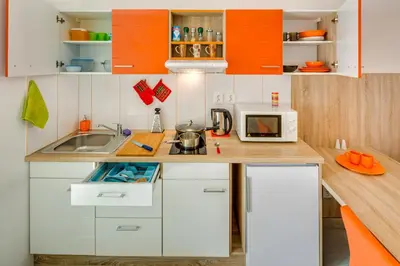 a small kitchen with orange and white cabinets at Apartements Studio 964 in Líbeznice