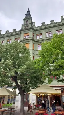 a large building with tables and an umbrella in front of a tree at Apartments 39 Wenceslas Square in Prague