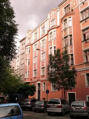 a large pink building with cars parked in front of it at Apartment Sense of Zizkov in Prague