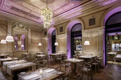 a restaurant with tables and chairs and a chandelier at COSMOPOLITAN Hotel Prague in Prague