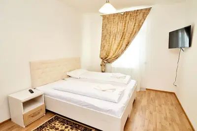 a white bedroom with a bed and a television at Kasablanka apartments in Prague
