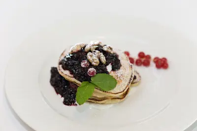 a plate with a stack of pancakes with berries at Hotel Bílý Páv in Benátky nad Jizerou
