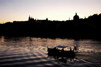 a boat in the water with the sun setting at Prague Studio Old Town in Prague