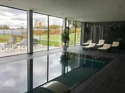 a house with a swimming pool with tables and chairs at Hotel Panství Dlouhá Lhota in Dlouhá Lhota
