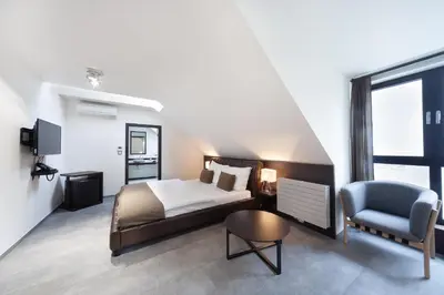 a bedroom with a bed and a chair and a television at Hotel Panství Dlouhá Lhota in Dlouhá Lhota