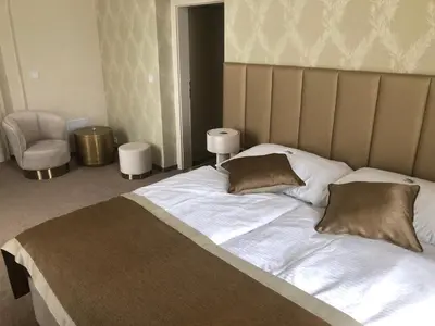 a bedroom with a large bed and a chair at Hotel Panství Dlouhá Lhota in Dlouhá Lhota