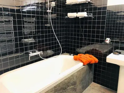 a black tiled bathroom with a tub and a sink at Hotel Panství Dlouhá Lhota in Dlouhá Lhota