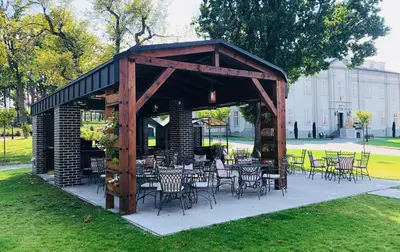 a pavilion with tables and chairs in a park at Hotel Panství Dlouhá Lhota in Dlouhá Lhota