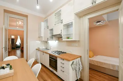 a kitchen with white cabinets and a table and a bed at Stunning Charles Bridge Apartment in Prague