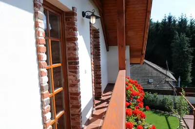 a balcony of a house with flowers and a window at Starý Svět in Wotitz