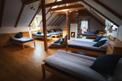 a attic room with four beds and a room with chairs at Starý Svět in Wotitz