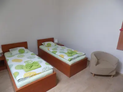 two twin beds in a room with a chair at Agropenzion U Bartousku in Malíkovice