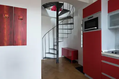 a kitchen with red cabinets and a spiral staircase at Prague Letna Apartments in Prague