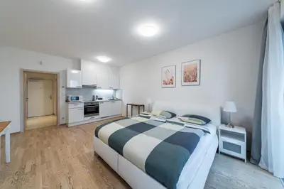 a bedroom with a large bed and a kitchen at Garden Towers Apartments in Prague