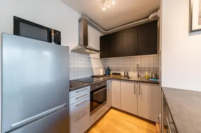 a kitchen with white cabinets and a stainless steel refrigerator at Garden Towers Apartments in Prague