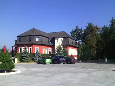 a large house with cars parked in a parking lot at Penzion v Zálesí in Mladá Boleslav