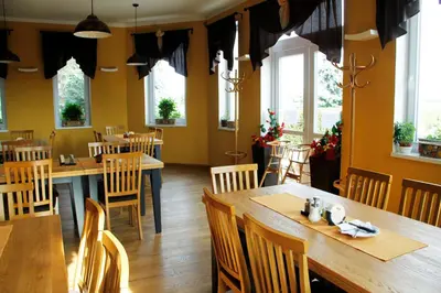a restaurant with wooden tables and chairs and windows at Penzion v Zálesí in Mladá Boleslav