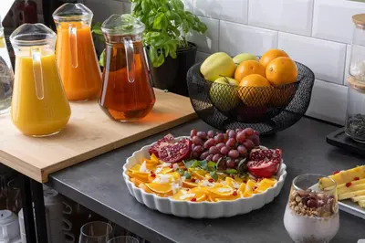 a table with a plate of fruit and a bowl of juice at Hotel AMITY in Prague