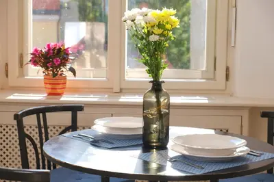 a table with plates and a vase with flowers on it at Pawlansky Prague Apartments in Prague