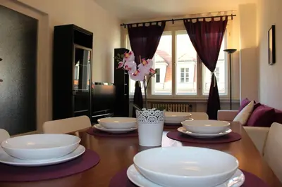 a dining room table with white dishes on it at Go Native Prague Apartment in Prague