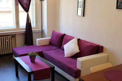 a living room with a purple couch and a table at Go Native Prague Apartment in Prague