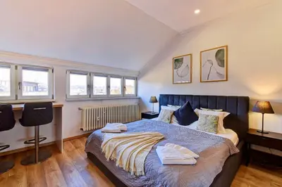 a bedroom with a large bed and some windows at Beautiful Apartment Dlouhá in Prague