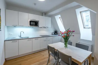 a kitchen with white cabinets and a wooden table with flowers at Harrachovsky Palace in Prague