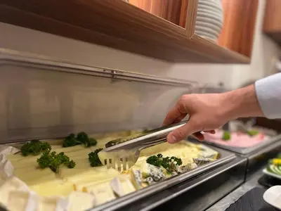 a person is preparing food in a kitchen at Hotel Garden Court in Prague