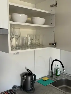 a kitchen counter with glasses on shelves and a sink at Apartments in Residence Garden Towers in Prague
