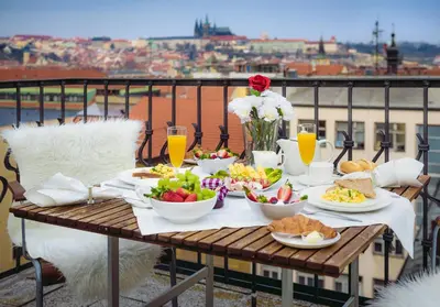a table with food and drinks on a balcony at A/C + TERRACE Breakfast at Tiffany’s in Prague