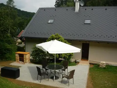 a table and chairs with an umbrella in front of a house at Hájovna Bukovec in Bukovec