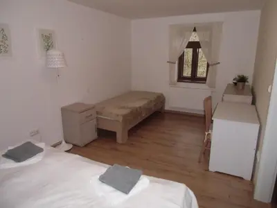 a bedroom with two beds and a table and a window at Hájovna Bukovec in Bukovec