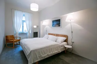 a white bedroom with a bed and a chair at Apartments At The Blue Duckling in Prague