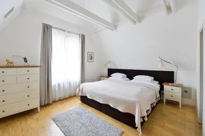 a white bedroom with a large bed and a dresser at Eclectic Loft with Terrace in Prague