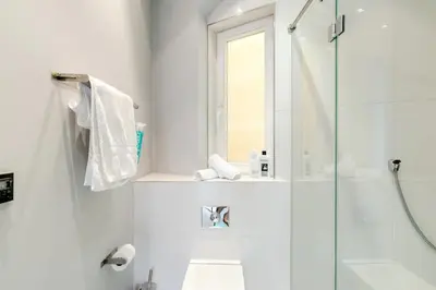 a white bathroom with a shower and a sink at Prague Days - One-bedroom Apartment with Workspace and iMac in Vinohrady in Prague