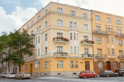 a large yellow building with cars parked in front of it at Prague Days - One-bedroom Apartment with Workspace and iMac in Vinohrady in Prague