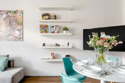 a dining room with a white table and blue chairs at Prague Days - One-bedroom Apartment with Workspace and iMac in Vinohrady in Prague