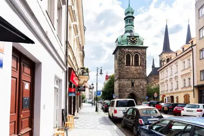 a city street with a clock tower and cars parked at 4 Trees Apartments by Adrez in Prague