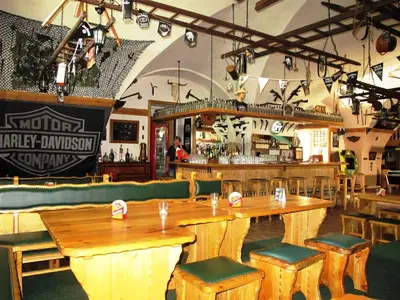 a restaurant with wooden tables and chairs and a bar at Hotel U Lišky in Hošťka