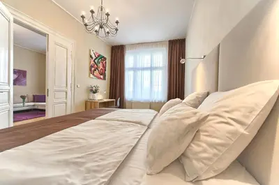 a large white bed in a bedroom with a chandelier at Maiselova 5 Apartment in Prague