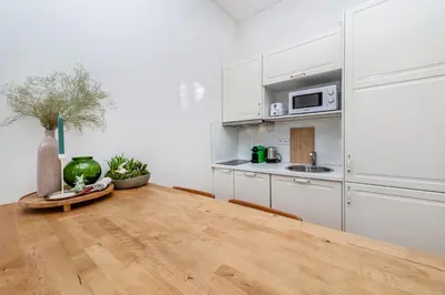 a kitchen with white cabinets and a wooden table at Quiet Apartment in The Old Town in Prague