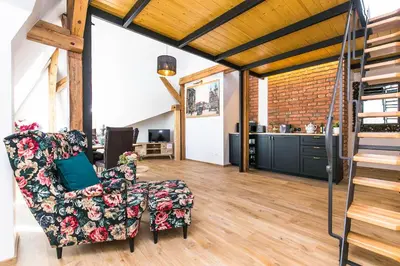 a living room with a chair and a staircase at The Old Town Square & Parizska Apartments in Prague