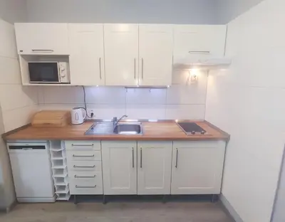 a small kitchen with white cabinets and a sink at Alisa Apartments in Kostomlaty