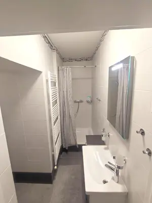 a white bathroom with a sink and a shower at Alisa Apartments in Kostomlaty