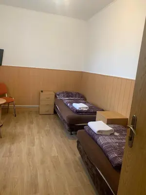 a room with two beds and a table and a door at Penzion Mánes in Krabčice