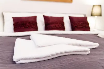 two white towels on a bed with red pillows at Residence Glamour Excellent in Prague