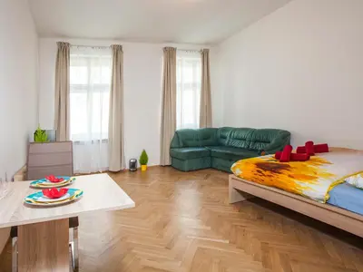 a living room with a bed and a green couch at Beautiful Central Apartment Thámova in Prague