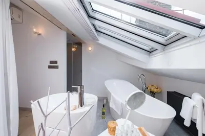 a bathroom with a white tub and a skylight at Wishlist Prague Residences - Old Town Square in Prague