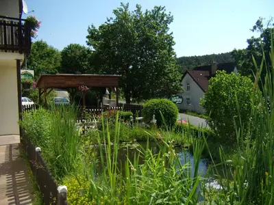 a garden with a pond and a gazebo at Penzion Lida in Srbsko