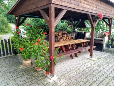 a wooden gazebo with a bench and flowers at Penzion Lida in Srbsko